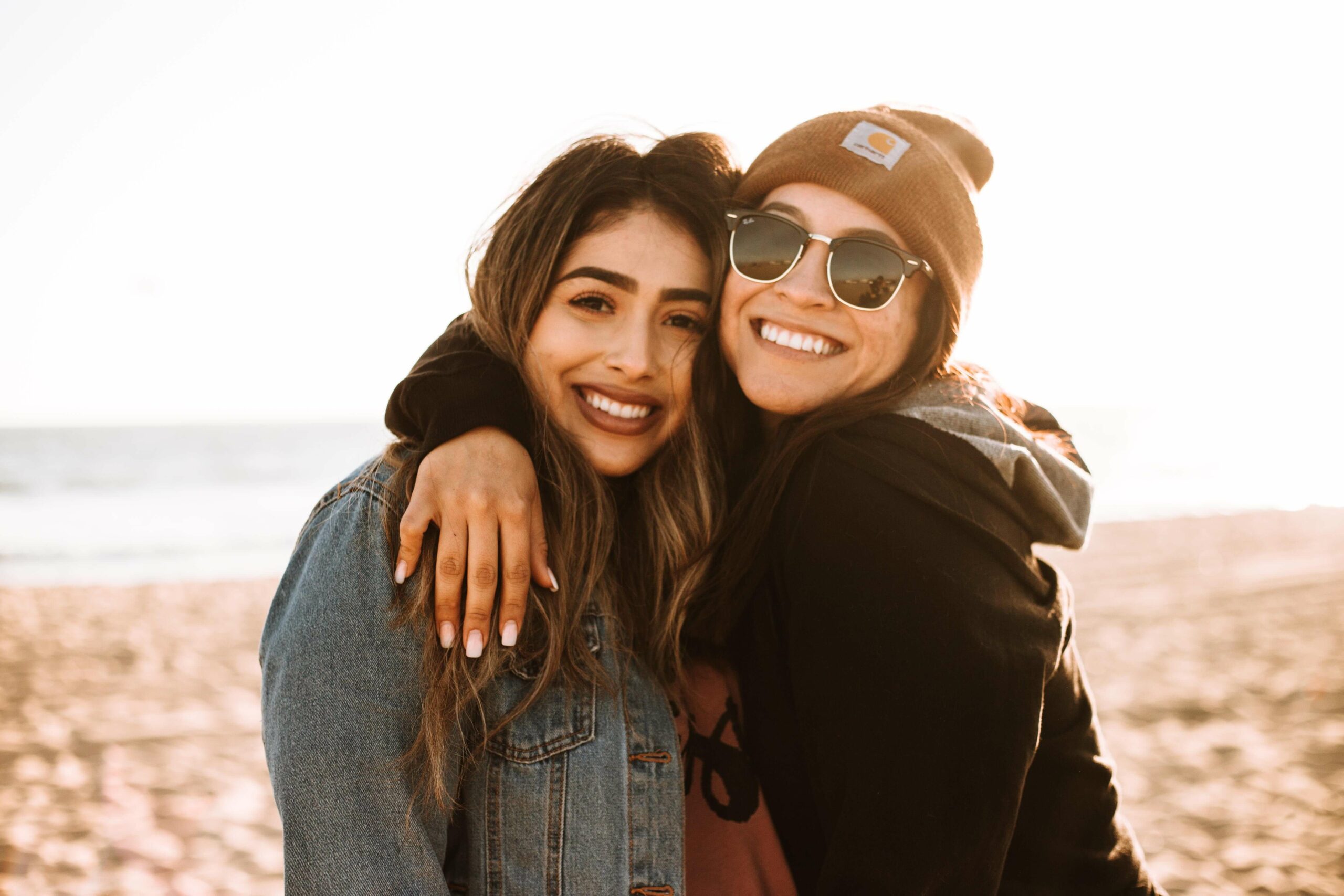 Drug recovery programs portrait of two cheerful young women standing together and looking at camera isolated over blurred background