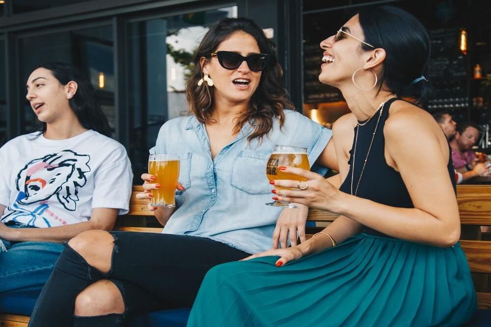 Female friends cheering with beer at music festival, alcohol and drug recovery center