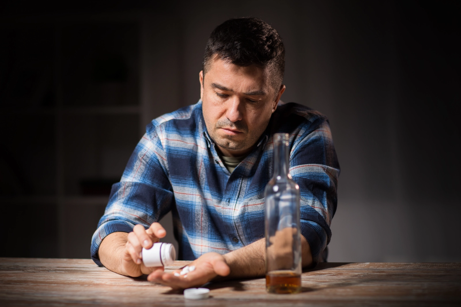generic antabuse is a drug that can act as a drinking deterrant; man with a beer takes pill from bottle