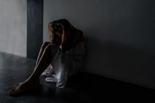 Bad Trip Symptoms: A woman sitting on the floor in a dark room in extreme distress.