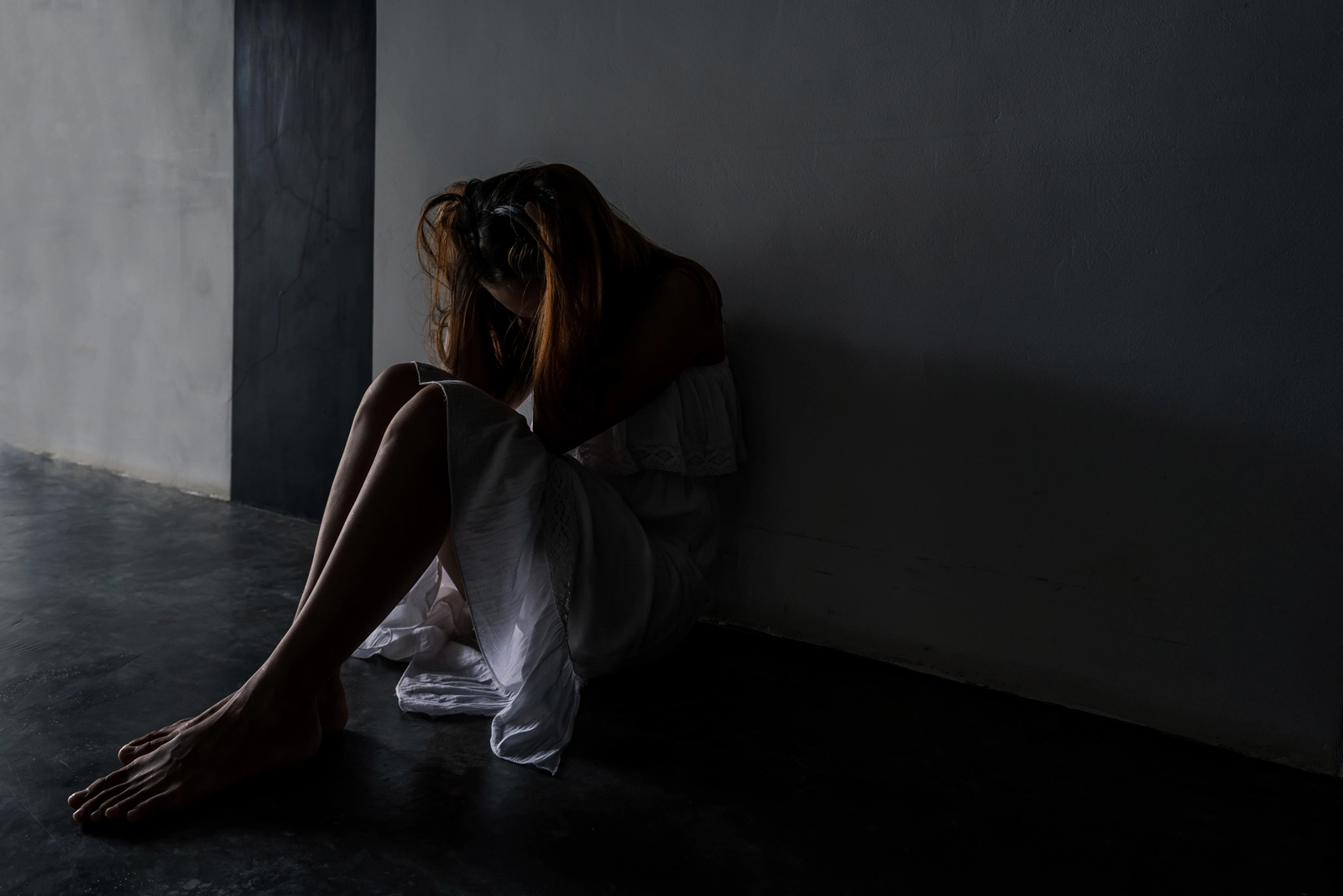 Bad Trip Symptoms: A woman sitting on the floor in a dark room in extreme distress.